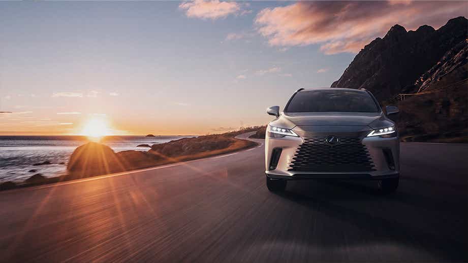 Front view of a Lexus RX on a coastal road at sunset