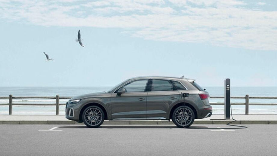 side view of a Manhattan Gray Metallic Audi Q5 charging at a station by the sea