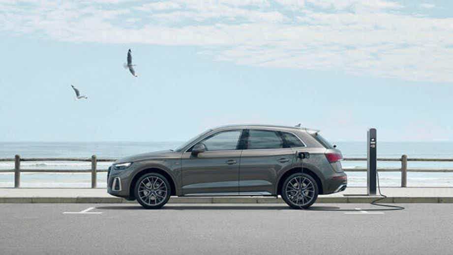 side view of a Manhattan Gray Metallic Audi Q5 charging at a station by the sea