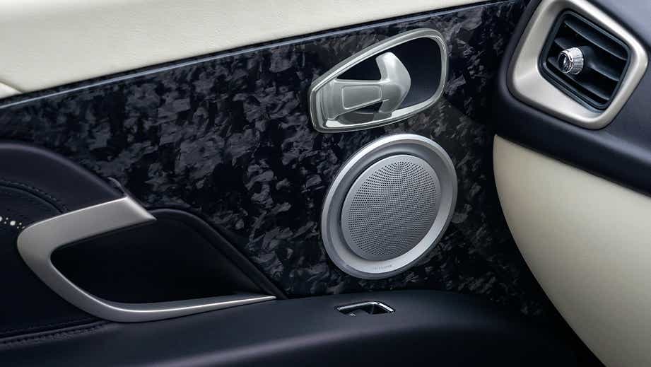Interior door panel of an Aston Martin DB11 featuring speaker and handle