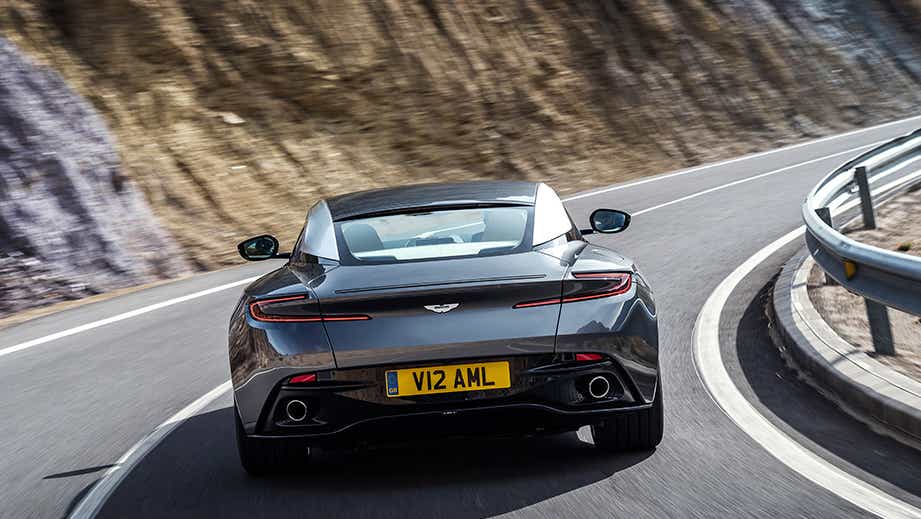 Rear view of an Aston Martin DB11 driving on a winding road