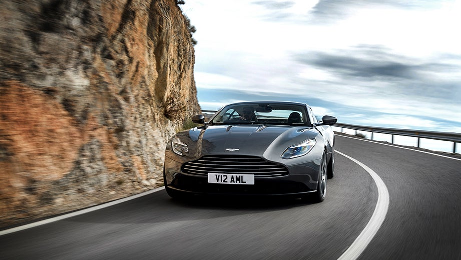 Front view of an Aston Martin DB11 driving on a curved mountain road