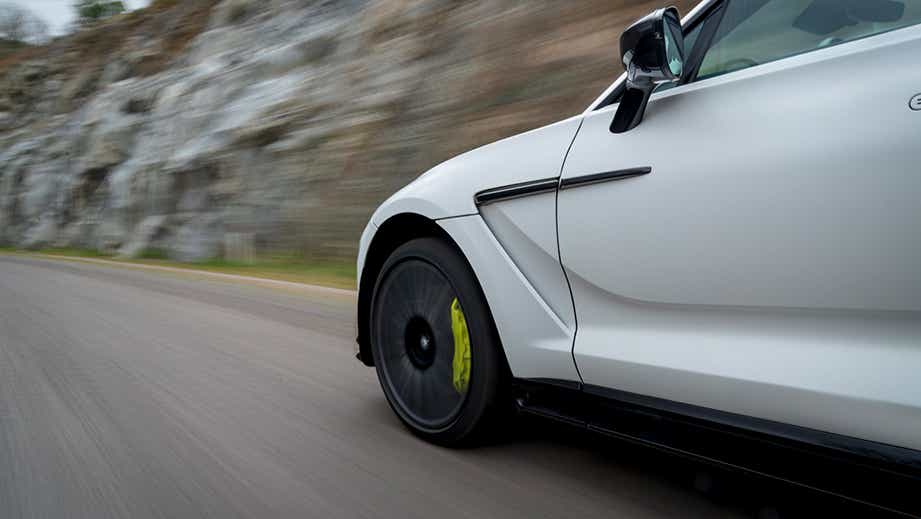 Front side view of an Aston Martin DBX driving on a road