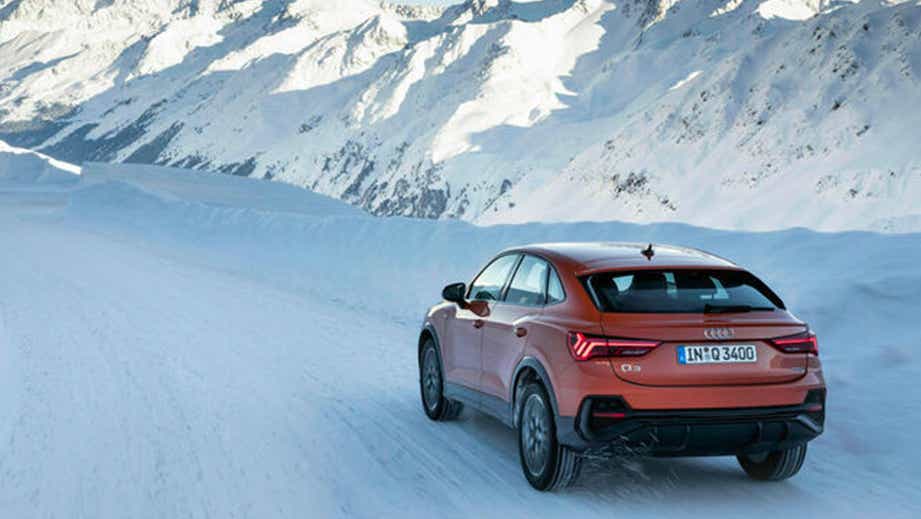 Rear three-quarter view of an Audi Q3 Sportback driving on a snow-covered mountain road