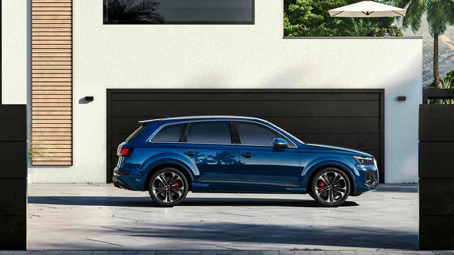 side view of an Audi Q7 parked in front of a modern house