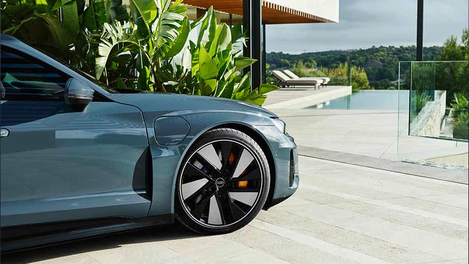 Front-side view of an Audi e-tron GT near a luxury poolside setting