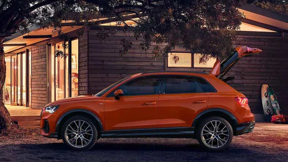 side view of an Audi Q3 with open tailgate in front of a house