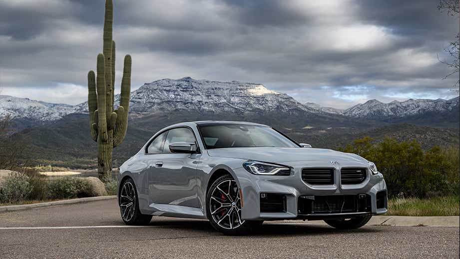front three-quarter view of a BMW M2 on a scenic mountain road