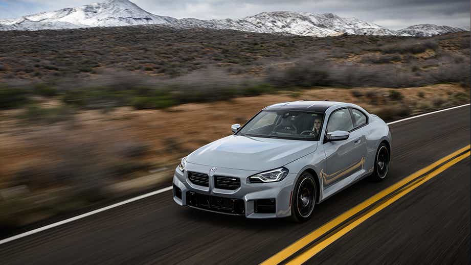 front three-quarter view of a BMW M2 on a scenic mountain road