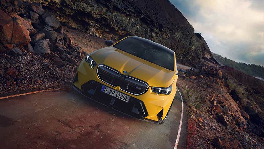 Front view of a BMW M5 on a winding cliffside road