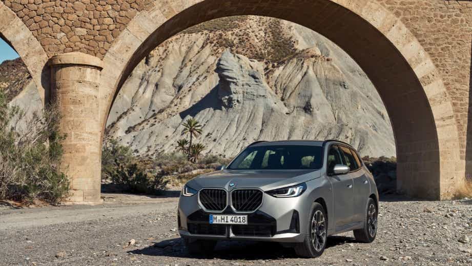 front three-quarter view of a BMW X3 under a stone arch bridge