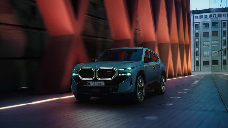 front view of a BMW XM driving through a modern urban bridge
