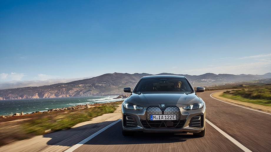 front view of a Black Sapphire BMW i4 on a scenic coastal road