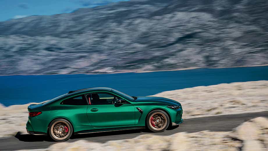 side view of a BMW M4 CS coupe driving on scenic road