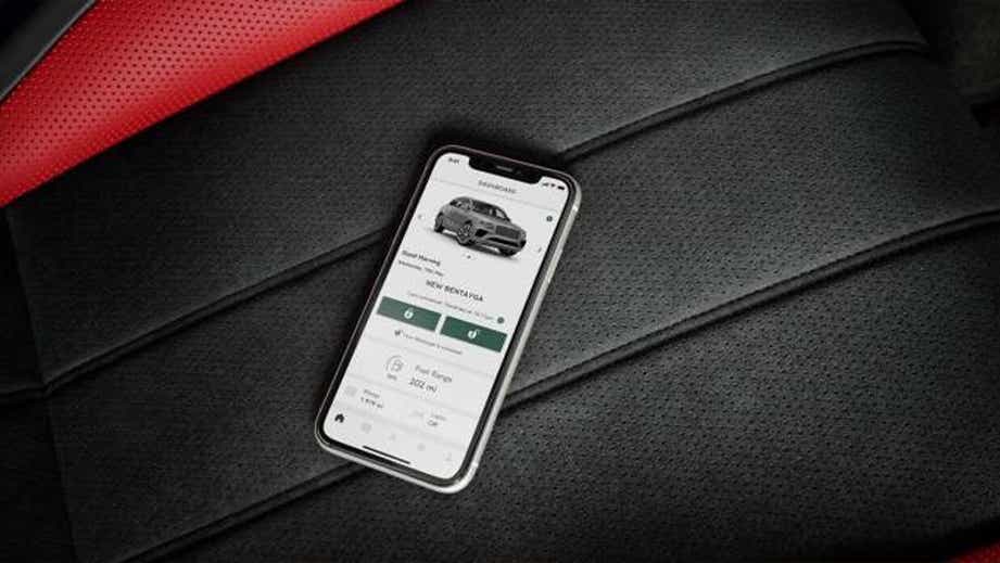 Close-up of a smartphone displaying Bentley Bentayga interface on car seat