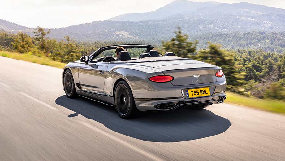 rear three-quarter of a Bentley Continental convertible driving on a scenic road