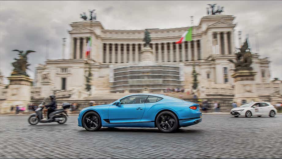 side view of a Blue Crystal Bentley Continental in front of a historic building