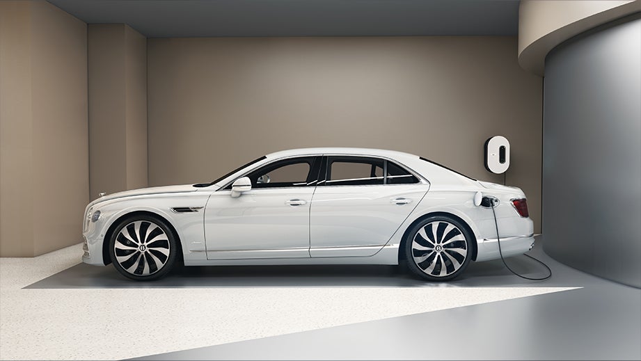side view of a Glacier White Solid Bentley Flying Spur charging