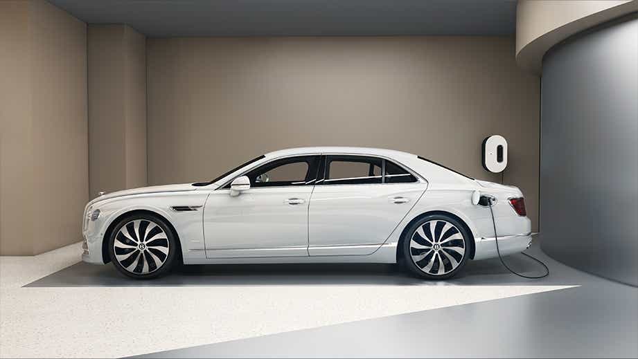 side view of a Glacier White Solid Bentley Flying Spur charging