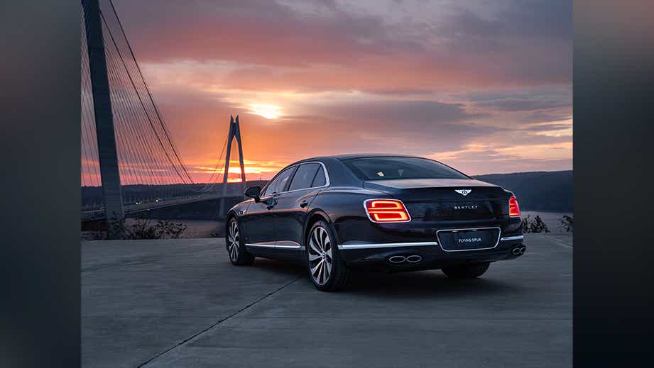 rear three-quarter view of a Bentley Flying Spur at sunset