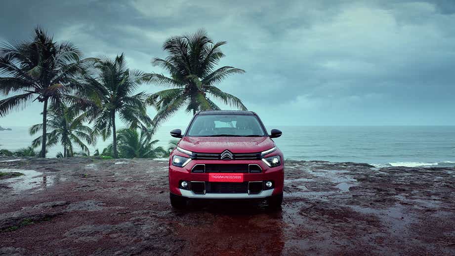 Front view of a Citroen Basalt by the seaside with palm trees
