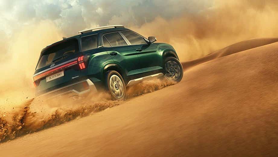rear three-quarter view of a Hyundai Alcazar driving on sand dunes