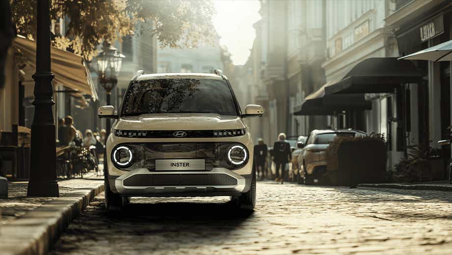 Front view of a Hyundai Inster EV on a cobblestone city street