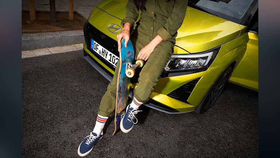 Front view of a Hyundai i20 N Line with a person sitting on the hood holding a skateboard