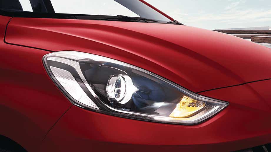 Headlight close-up of a Fiery Red Hyundai Grand i10 Nios