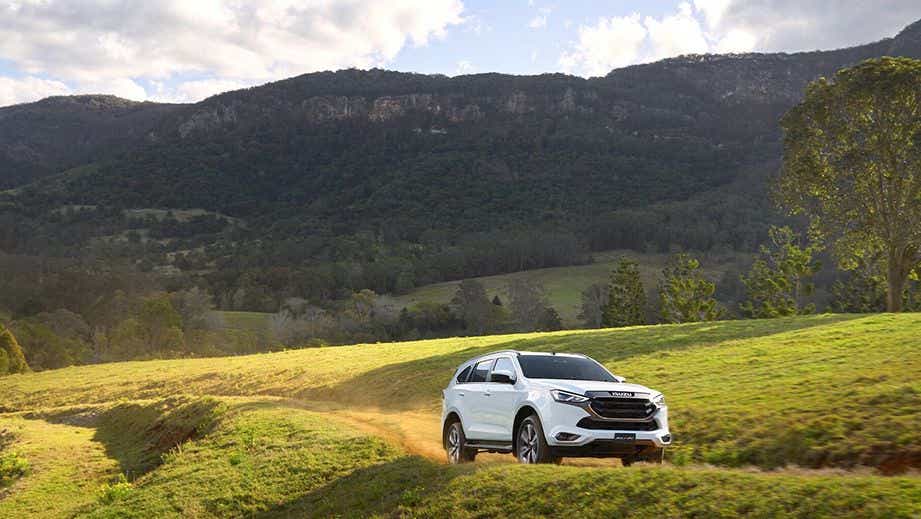 front three-quarter view of an Isuzu MU-X driving on a grassy path