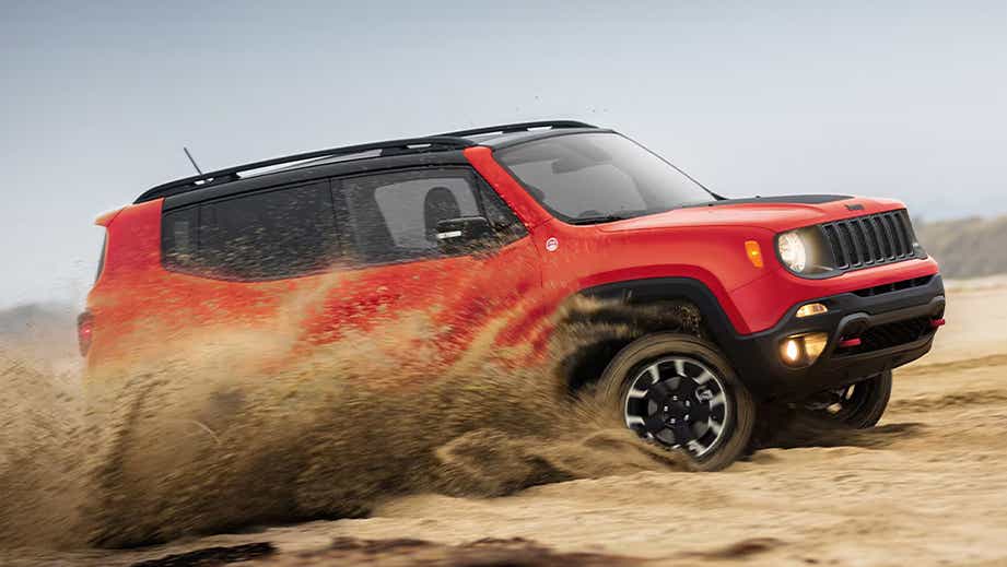 side action view of a Jeep Renegade driving through sand