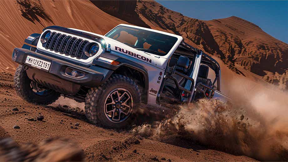Front three-quarter view of a Bright White Jeep Wrangler Rubicon off-roading in sand dunes