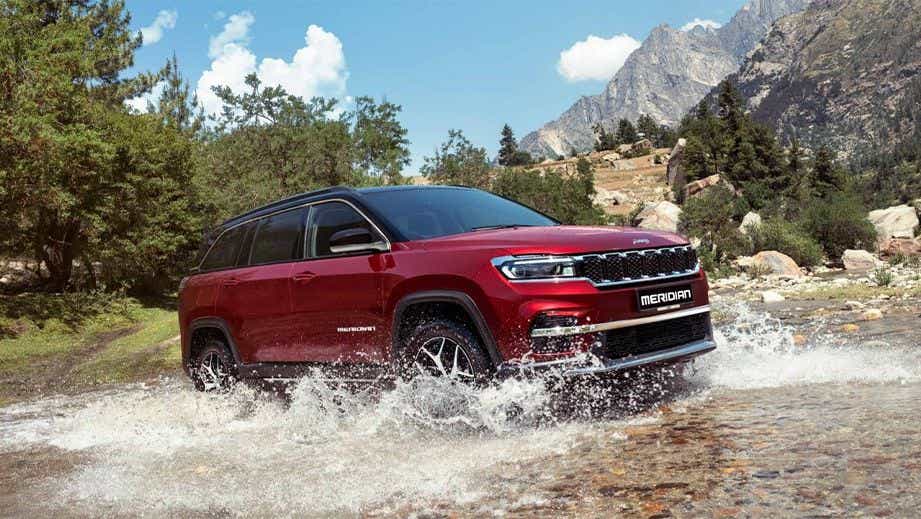 front three-quarter view of a Jeep Meridian 2022-2023 driving through water outdoors