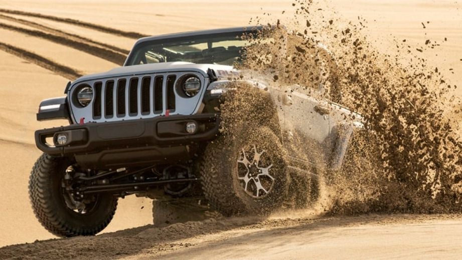 Front three-quarter view of a Jeep Wrangler 2021-2023 driving off-road