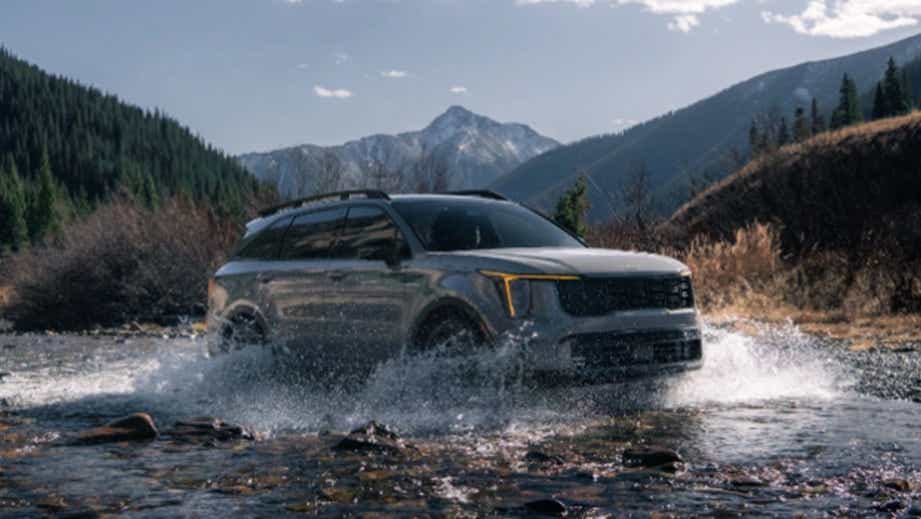 front three-quarter view of a Gravity Grey Kia Sorento crossing a stream