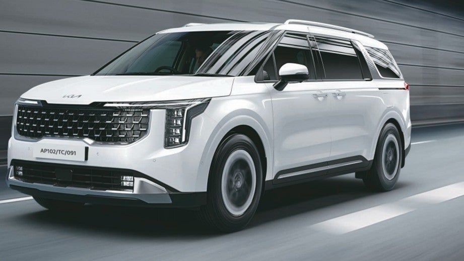 front three-quarter view of a Glacier White Pearl Kia Carnival