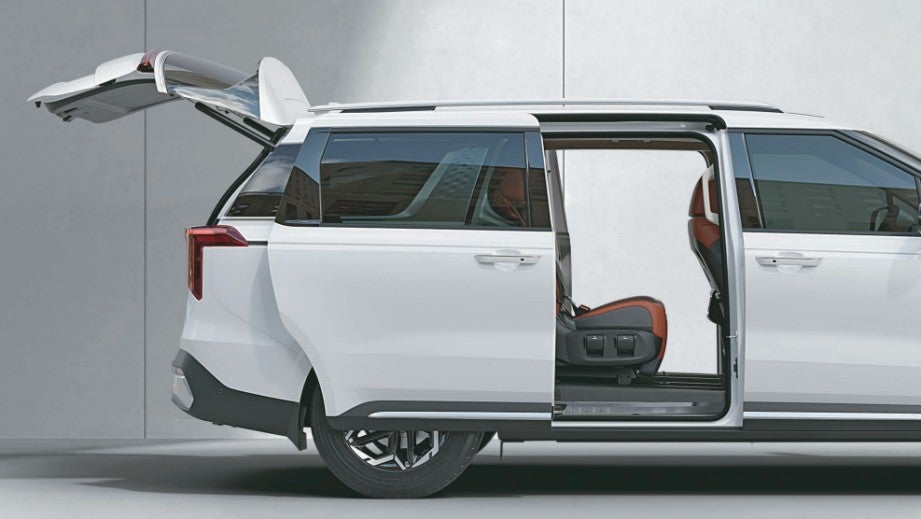 side view with open sliding door and boot of a Glacier White Pearl Kia Carnival