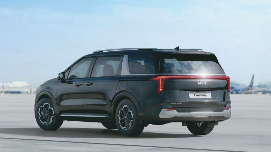 rear three-quarter of a Fusion Black Kia Carnival