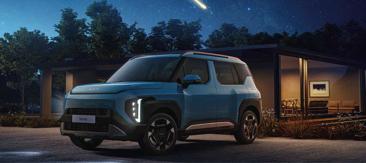 front three-quarter view of a Kia Syros at night