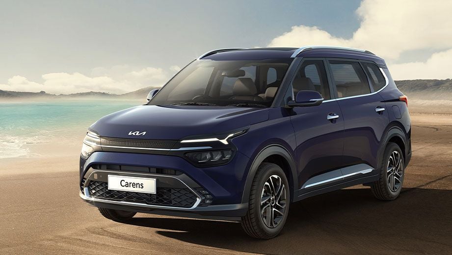 Front three-quarter view of a Kia Carens on a beach