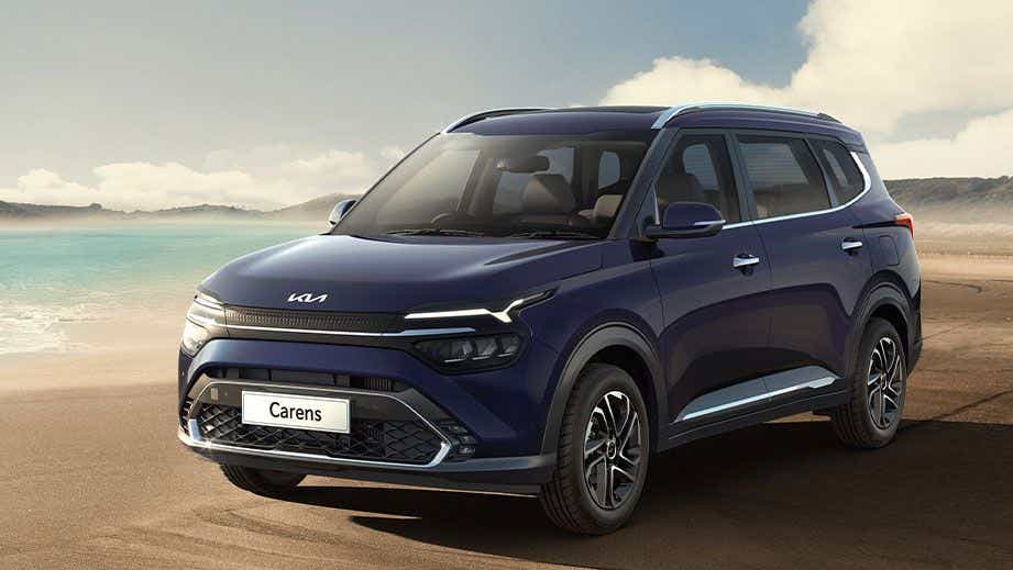 Front three-quarter view of a Kia Carens on a beach