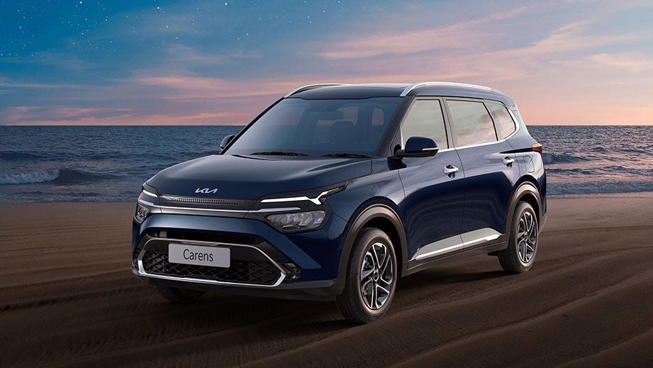 front three-quarter of a Kia Carens on a beach at sunset