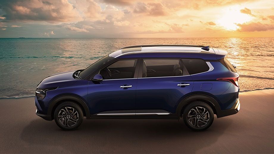 side view of a Kia Carens at a beach during sunset