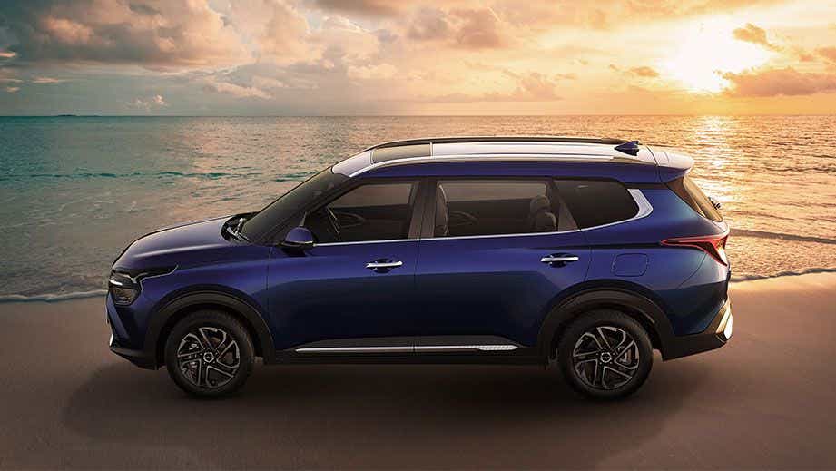 side view of a Kia Carens at a beach during sunset