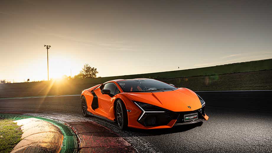 front three-quarter view of a Lamborghini Revuelto on a racetrack at sunset