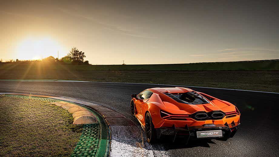 Rear three-quarter view of a Lamborghini Revuelto on a racetrack at sunset