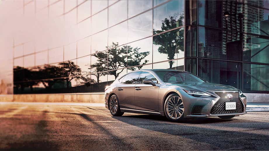 front three-quarter view of a Lexus LS in front of a modern glass building