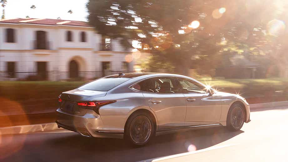 rear three-quarter view of a Lexus LS sedan driving on a sunny street