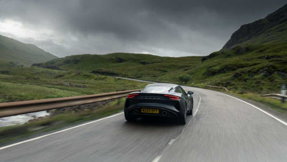 rear view of a Lotus Emira driving on a winding road