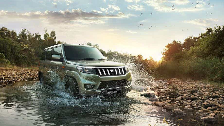 Front three-quarter view of a Mahindra Bolero Neo driving through water